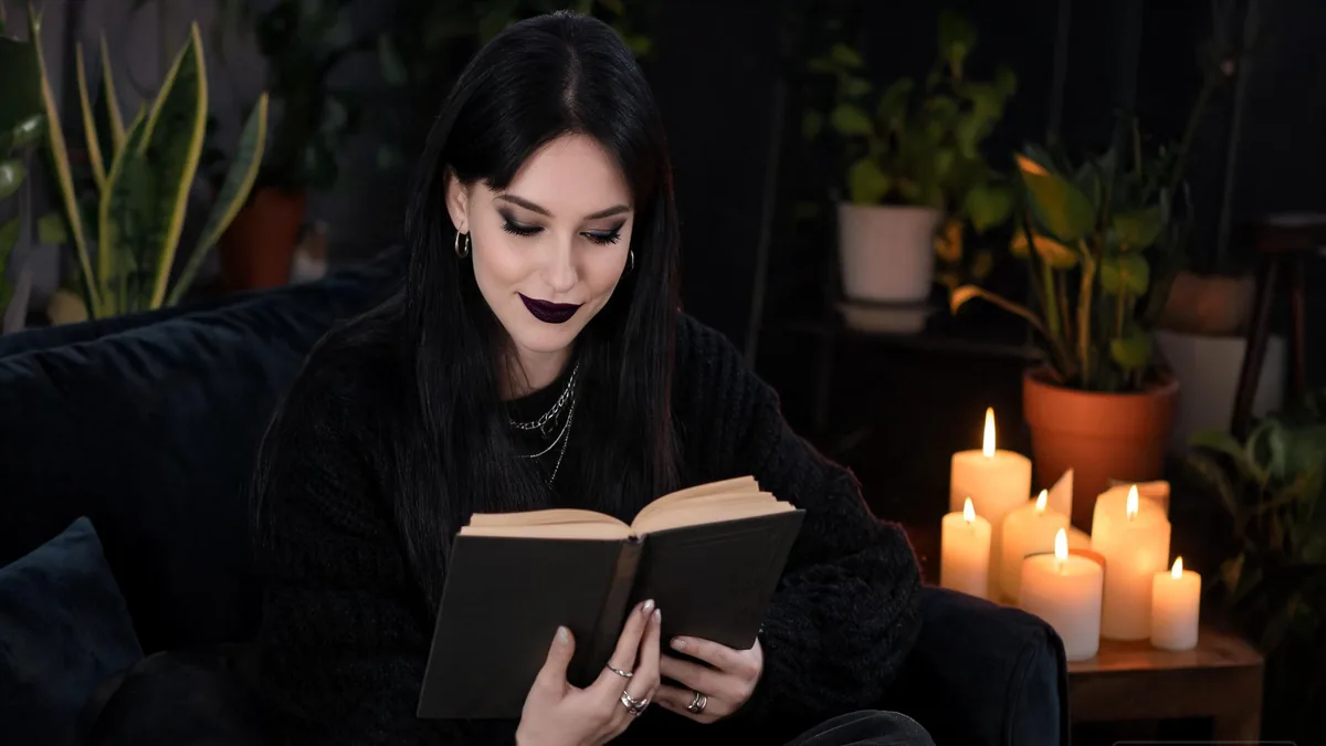 The defining goth personality traits, a cozy reader curled up with a gothic novel by candlelight, soft and warm under the dark style