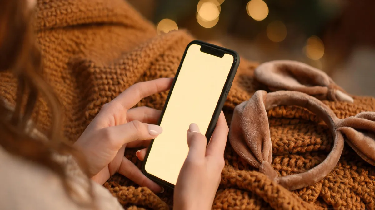 Kemonomimi AI girlfriend companion experienced through a phone, with a soft animal-ear headband and a warm cozy evening mood