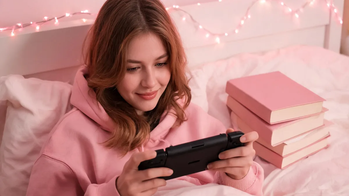 Otome-style AI girlfriend experience, a cozy evening scene with a young woman playing a handheld romance game on her bed