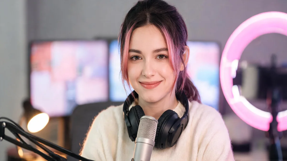 VTuber-style streamer with pastel pink and blue hair smiling at her colorful gaming desk, the bright, friendly mood that defines the VTuber world